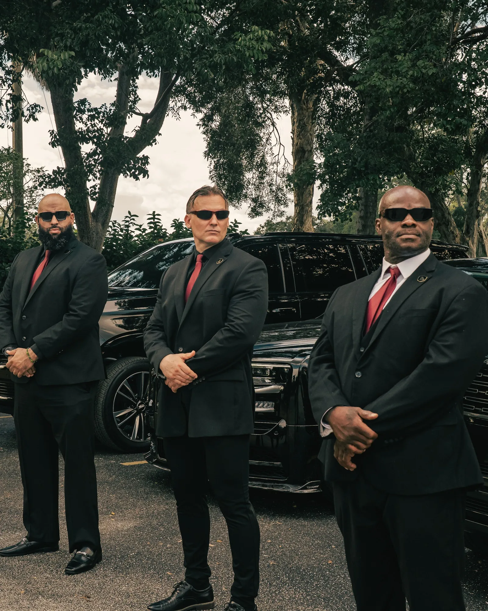Prestige Guard officers in dark suits standing in front of the company vehicles
