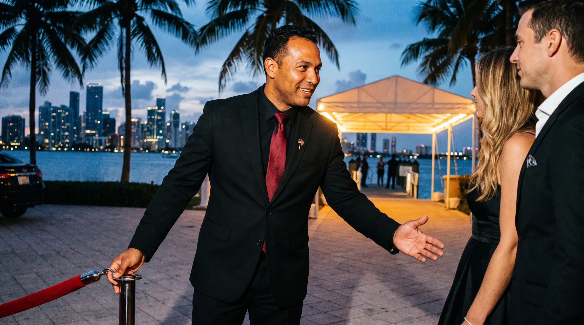 Officer welcoming arriving guests at the roped entrance of a waterfront venue at dusk